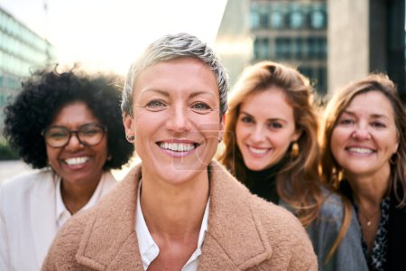 Foto de Grupo de retratos de mujeres de negocios multirraciales empoderadas de diversas edades que miran sonriendo a la cámara con expresión feliz y segura. Caucásico atractiva mujer con pelo corto de pie en primer plano - Imagen libre de derechos