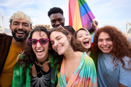 Diverse group of happy young people taking funny selfie for social media celebrating gay pride festival day. Lgbt community concept cheerful friends outdoors. Generation z enjoy party.