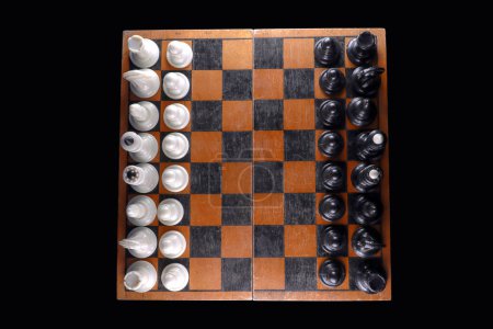 Foto de Antiguo tablero de ajedrez con piezas sobre un fondo negro aislado. Vista desde arriba - Imagen libre de derechos