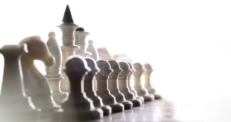 Close-up of white chess pieces along the board on a light background.