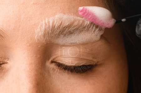 Foto de Parte de la cara femenina en las cejas cuya espuma de limpieza se aplica cuidadosamente con un cepillo especial - Imagen libre de derechos