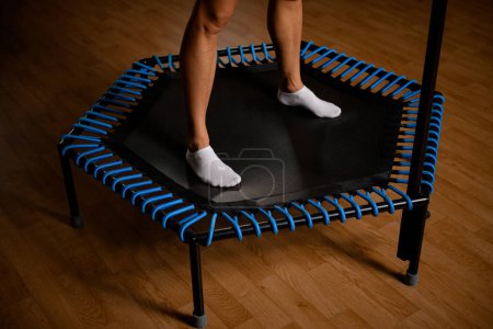 Photo for Close-up of beautiful muscular female legs in white socks on mini trampoline in the gym. Cropped photo. - Royalty Free Image