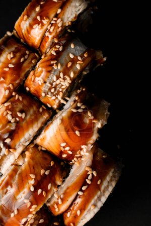 Photo for Cropped photo of close-up top view of sushi rolls Philadelphia with smoked eel with soy sauce and sesame seeds on dark background. Sushi menu. Japanese food. - Royalty Free Image