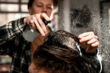 Photo for Great close-up view of head hair of male client which barber wets by spray and combs. Man barber making modern male hairstyle - Royalty Free Image