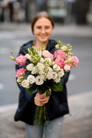 Photo for Young woman holding fresh colorful bouquet of eustoma flowers in hands. Focus on flovers. Blurred background - Royalty Free Image
