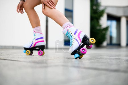 Téléchargez les photos : Plan recadré de jambes de femmes dans des chaussures de patins à roulettes vintage colorées isolées sur fond de mur blanc. Patineuse. Rue en dehors du mode de vie urbain - en image libre de droit