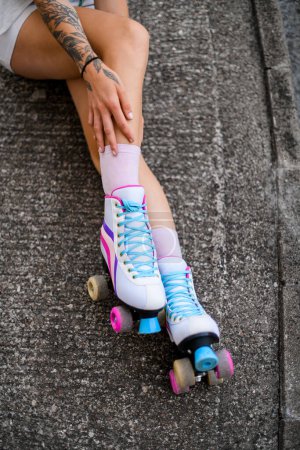 Téléchargez les photos : Jambes féminines en patins à roulettes vintage colorés chaussures isolées sur fond d'asphalte gris. rue en dehors du mode de vie urbain - en image libre de droit