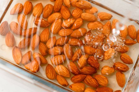 Almonds in the process of being soaked in a bowl of water for preparation.