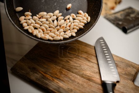 Whole almonds, beautifully peeled, rest gracefully on the warm wood surface of a cutting board.