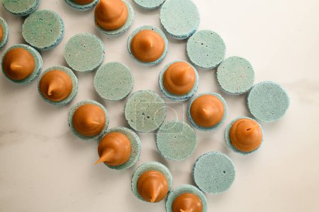 image capturing the meticulous process of incorporating cream into blue macarons.
