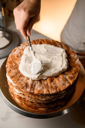 Witness the skilled process as a pastry chef carefully adorns a cake with whipped cream.