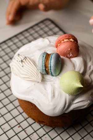 Schöne leckere Ostertorte mit weißem Zuckerguss, blauen und rosa Makronen und Limetten-Baiser dekoriert