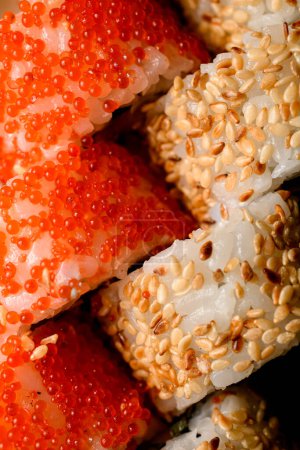 captivating perspective capturing a set of sushi rolls adorned with the delightful combination of tobiko caviar, sesame, and savory sauce.