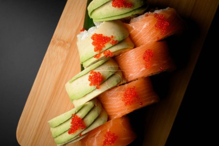 Top down glimpse showcasing sushi rolls featuring salmon, tobiko caviar, creamy Philadelphia cheese, avocado, and flavorful shrimp.
