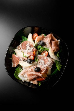 aerial perspective capturing the freshness of a salad with greens, olives, tuna, and Parmesan cheese, offering a delightful combination from above.