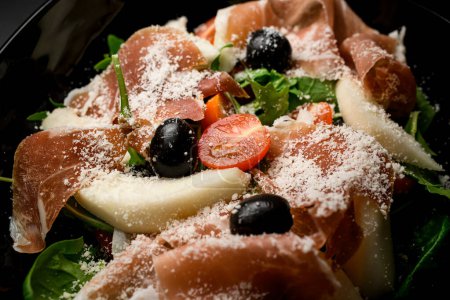 Detailansicht, die die lebendigen Farben und Texturen eines grünen Salats mit Oliven, Thunfisch und Parmesan in einem reizvollen und appetitanregenden Ensemble präsentiert.