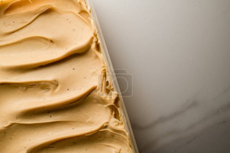 Crème moelleuse marron clair épaisse pour décorer des macarons à partir de farine d'amande sur une table en marbre