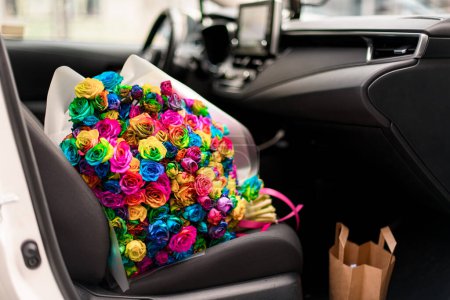 Bright multi-colored pink, lilac, yellow, blue, purple, green roses in a car. Composition of the beautiful flowers