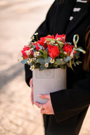 Lindo ramo de rosas incomparables en caja de cartón en manos de la chica sobre un fondo borroso