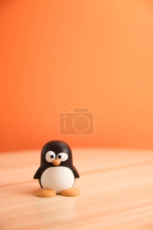 Photo for Image of Tux, the penguin that is the emblem of the GNU/Linux operating system. In the image it appears isolated on a table with copy space and orange background - Royalty Free Image