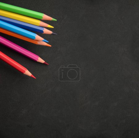 Téléchargez les photos : Image of some rainbow colored pencils on a black surface with some texture and copy space - en image libre de droit