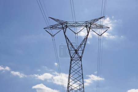 Photo for Image of a high voltage electrical transmission tower seen from the ground with blue sky with scattered clouds in the background - Royalty Free Image