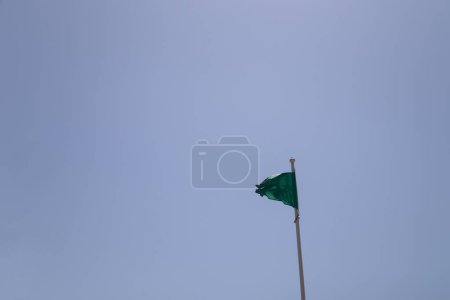Photo for Close-up of a green flag on a beach silhouetted against the blue summer sky and symbolizing that the sea water is suitable for bathing - Royalty Free Image