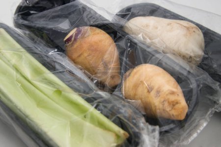 Close-up of some plastic packages that protect some pieces of vegetables for sale in a supermarket from the outside