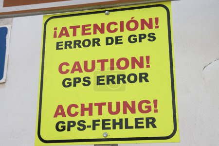 Close-up of a sign that warns of an error in the maps due to an error in the information given by the GPS maps. Sign in German, English and Spanish
