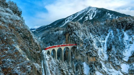 Téléchargez les photos : Paysage du train passant par la célèbre montagne de Filisur, en Suisse. Landwasser Viaduc patrimoine mondial avec train express dans les Alpes suisses neige paysages d'hiver. - en image libre de droit