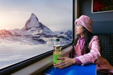 Foto de Turista mirando por la ventana disfrutando con la montaña Matterhorn mientras está sentado en el tren, Zermatt en Suiza. - Imagen libre de derechos