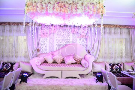 Foto de An elegantly staged traditional moroccan style wedding with large sofa for the wedding couple to sit and receive blessings from the guests, surrounded by beautiful  decor - Imagen libre de derechos