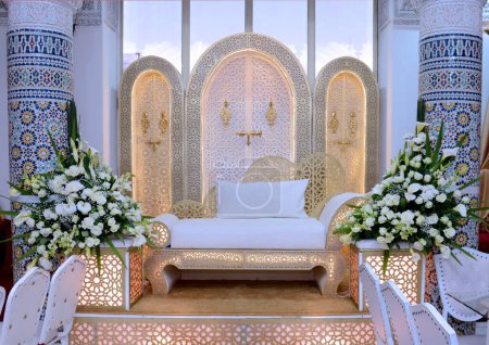 Téléchargez les photos : An elegantly staged traditional moroccan style wedding with large sofa for the wedding couple to sit and receive blessings from the guests, surrounded by beautiful  decor - en image libre de droit