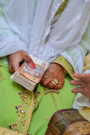 Photo for Moroccan bride holding Moroccan money with henna tattoos on her hands - Royalty Free Image