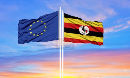 European Union and Uganda two flags on flagpoles and blue cloudy sky . Diplomacy concept, international relations