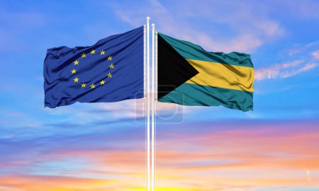 Foto de Unión Europea y Bahamas dos banderas en asta de bandera y cielo azul nublado. Concepto diplomático, relaciones internacionales - Imagen libre de derechos