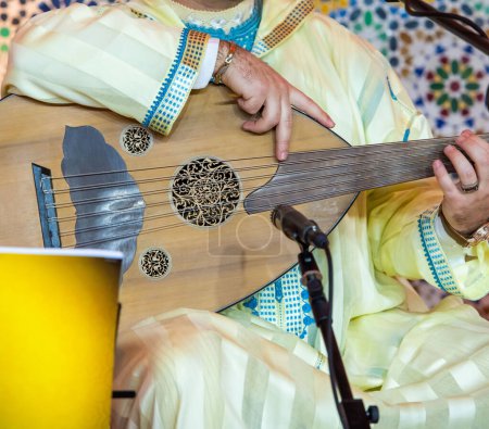 Téléchargez les photos : Un musicien marocain portant un djellaba marocain joue l'Oud - en image libre de droit