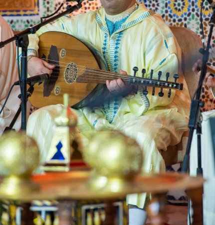 Téléchargez les photos : Un musicien marocain portant un djellaba marocain joue l'Oud - en image libre de droit