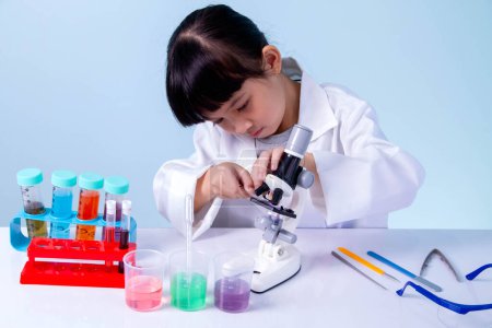 Photo for Kid in lab coat learning chemistry in school laboratory, business concepts, experimenting with chemical coloring or marketing planning - Royalty Free Image