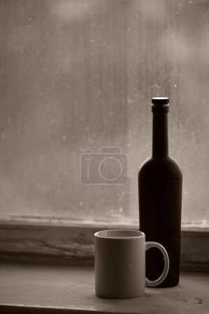Téléchargez les photos : Une tasse de thé et une bouteille par fenêtre - en image libre de droit