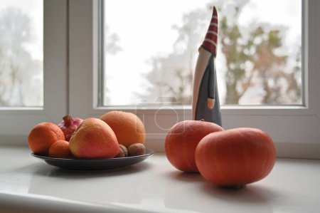 Téléchargez les photos : Nature morte avec santa claus jouet, citrouilles et fruits sur le rebord de la fenêtre - en image libre de droit