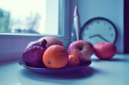 Foto de Un plato de frutas, calabazas y santa claus figura en el alféizar de la ventana - Imagen libre de derechos