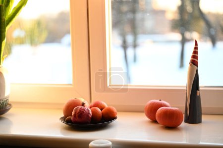 Téléchargez les photos : Une assiette de fruits, citrouilles et Père Noël figure sur le rebord de la fenêtre - en image libre de droit