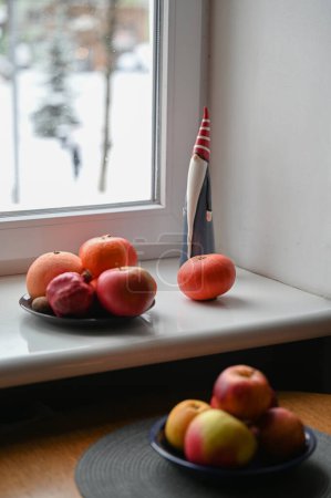 Téléchargez les photos : Nature morte avec santa claus jouet, citrouilles et fruits sur le rebord de la fenêtre - en image libre de droit