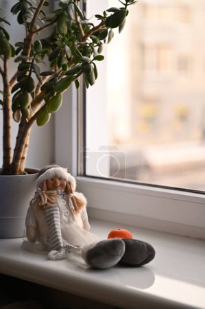 Photo for Plant and doll with tangerine   on a windowsill - Royalty Free Image