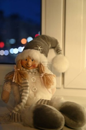 Foto de Navidad juguete chica en santa claus sombrero en alféizar de ventana - Imagen libre de derechos