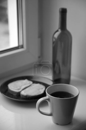 Foto de Botella, taza de café y tostadas en alféizar de la ventana - Imagen libre de derechos