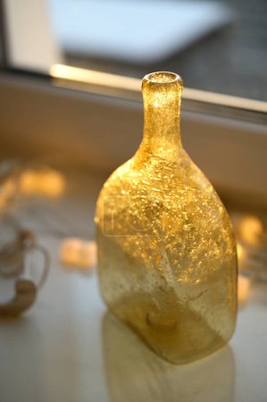 Photo for Christmas decoration with bottle, garland on a window sill - Royalty Free Image