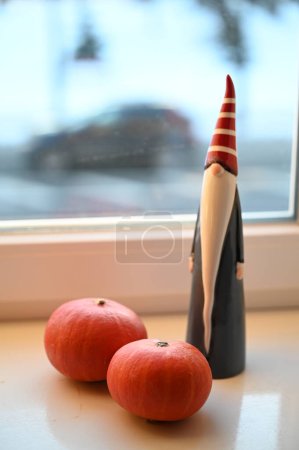 Foto de Una figura de gnomo y dos calabazas en un alféizar de ventana - Imagen libre de derechos