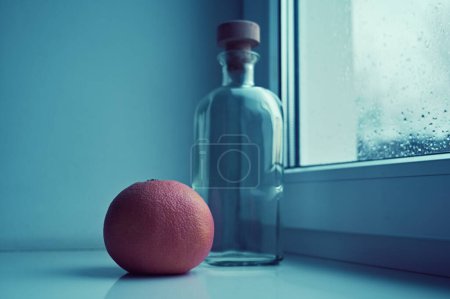 Foto de Botella de naranja fresca y vacía en el alféizar de la ventana - Imagen libre de derechos